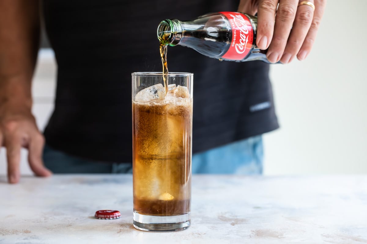 Adding coca cola to a Charro negro cocktail.