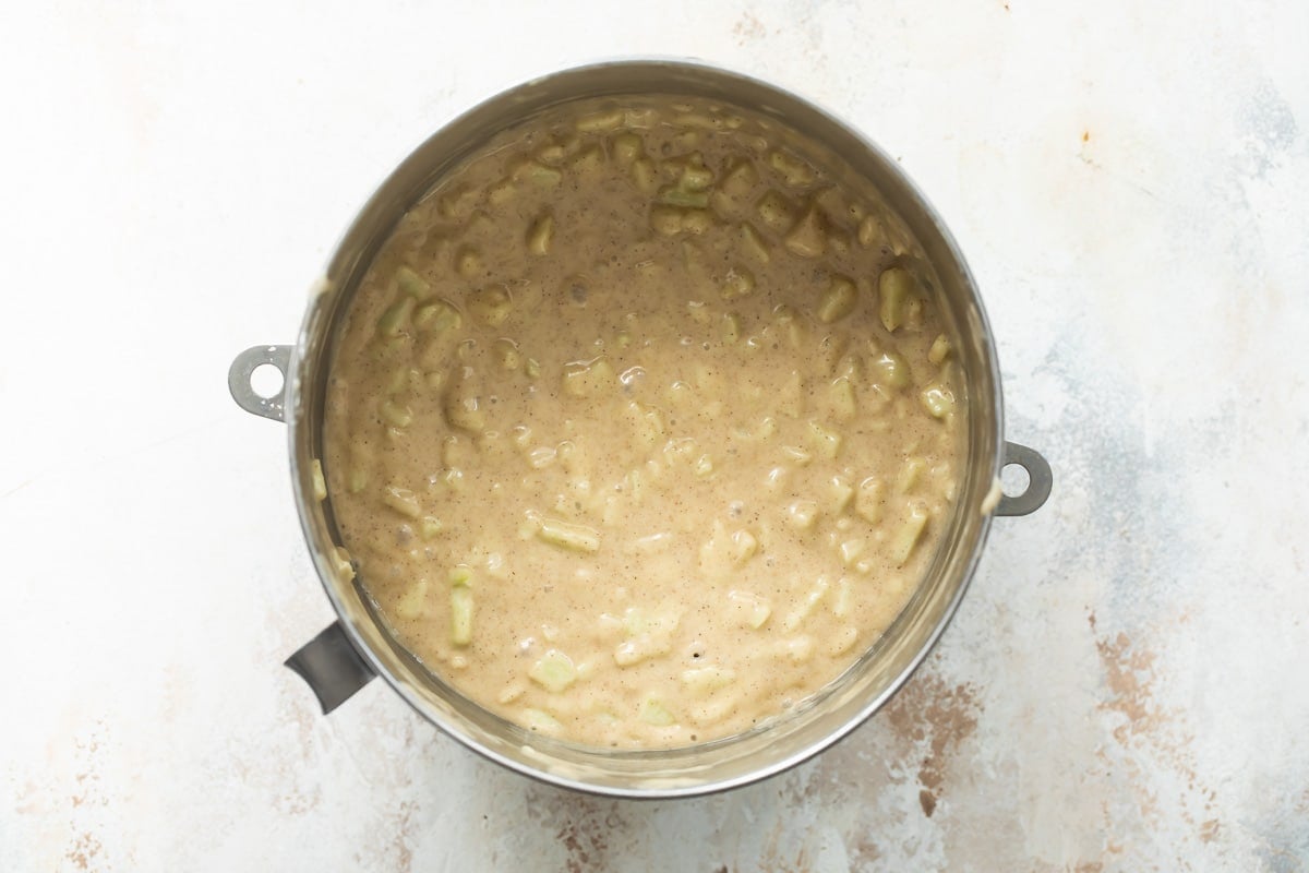 Cinnamon apple cake batter in a silver mixing bowl.