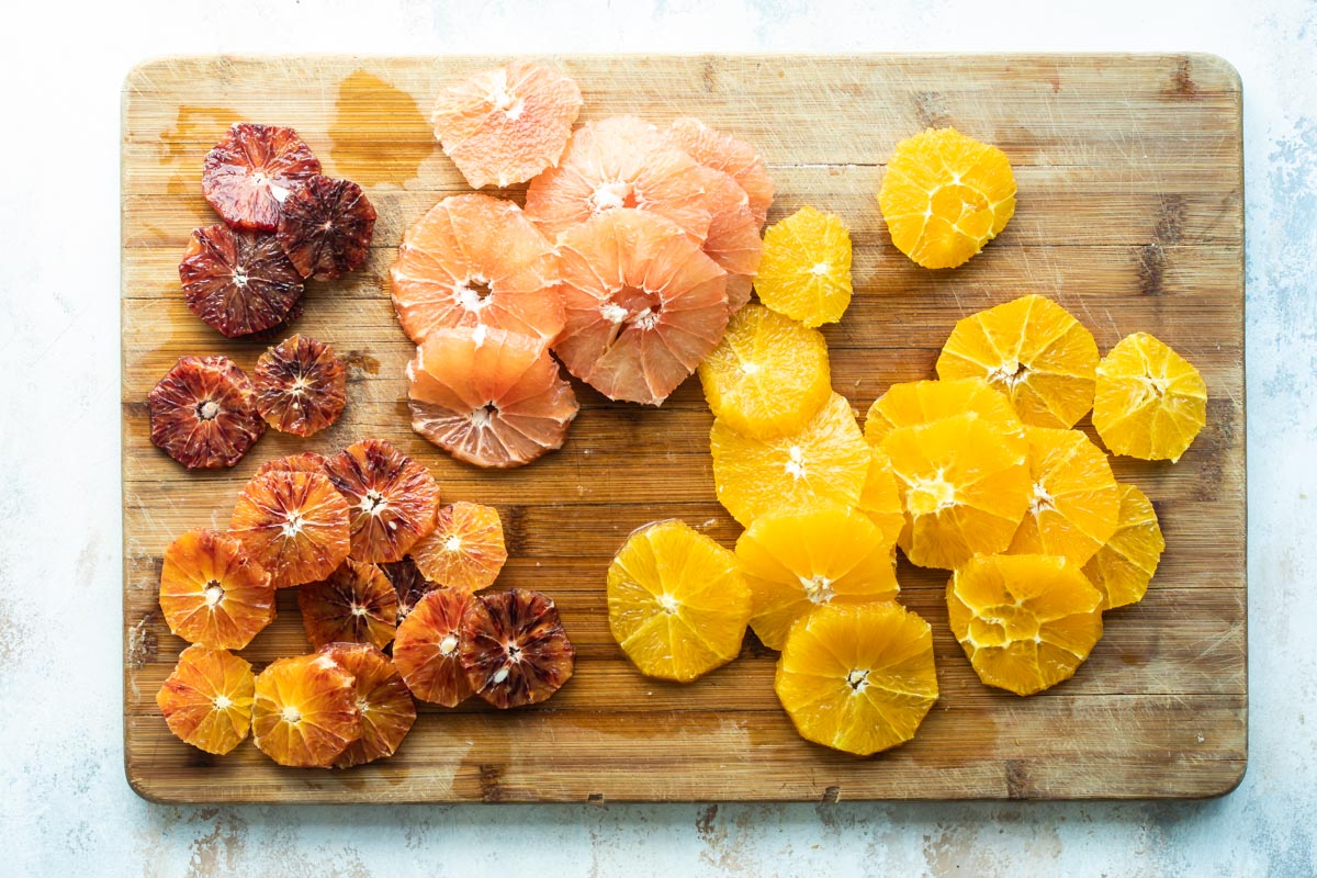 Citrus fruit cut up on a wooden cutting board.