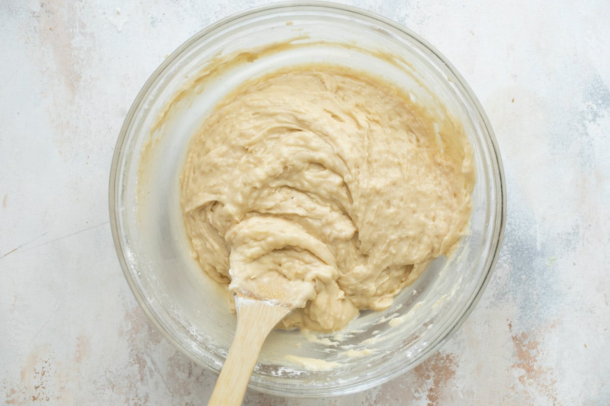 Coffee cake muffin batter in a glass mixing bowl with a wooden spoon.