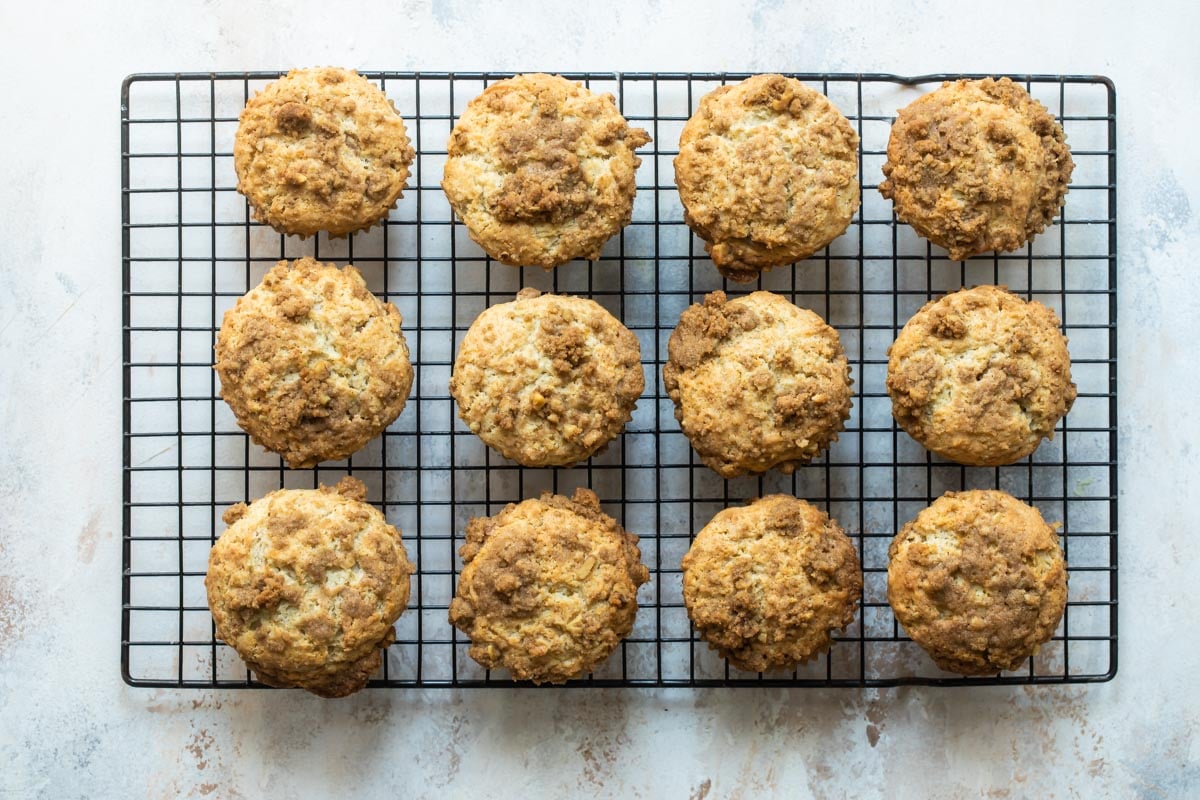 Twelve coffee cake muffins on a cooling rack.