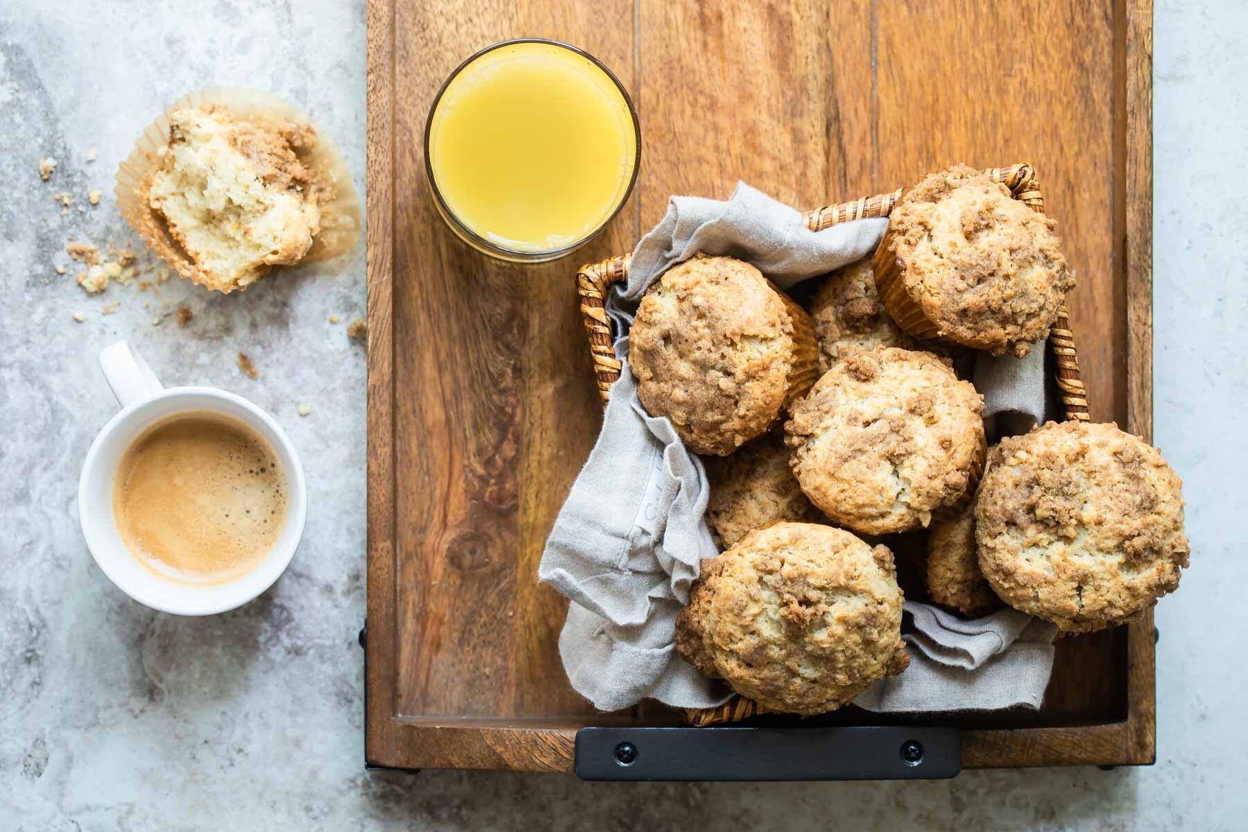 Coffee cake muffins in a basket on a wooden serving tray.