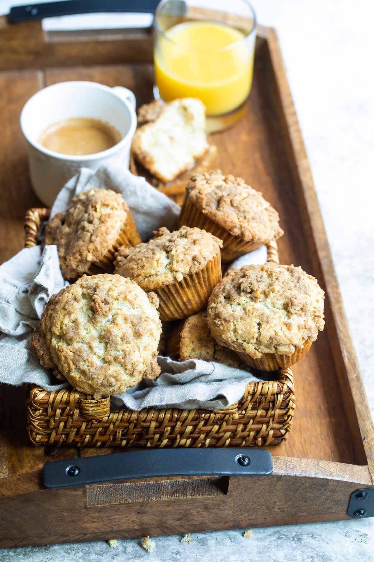 Coffee cake muffins in a basket on a wooden serving tray.