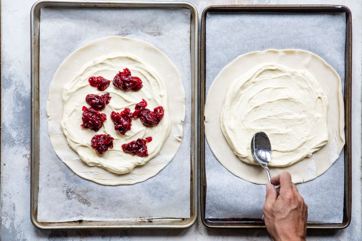 Two cookie sheets with cranberry cheesecake galettes being made.