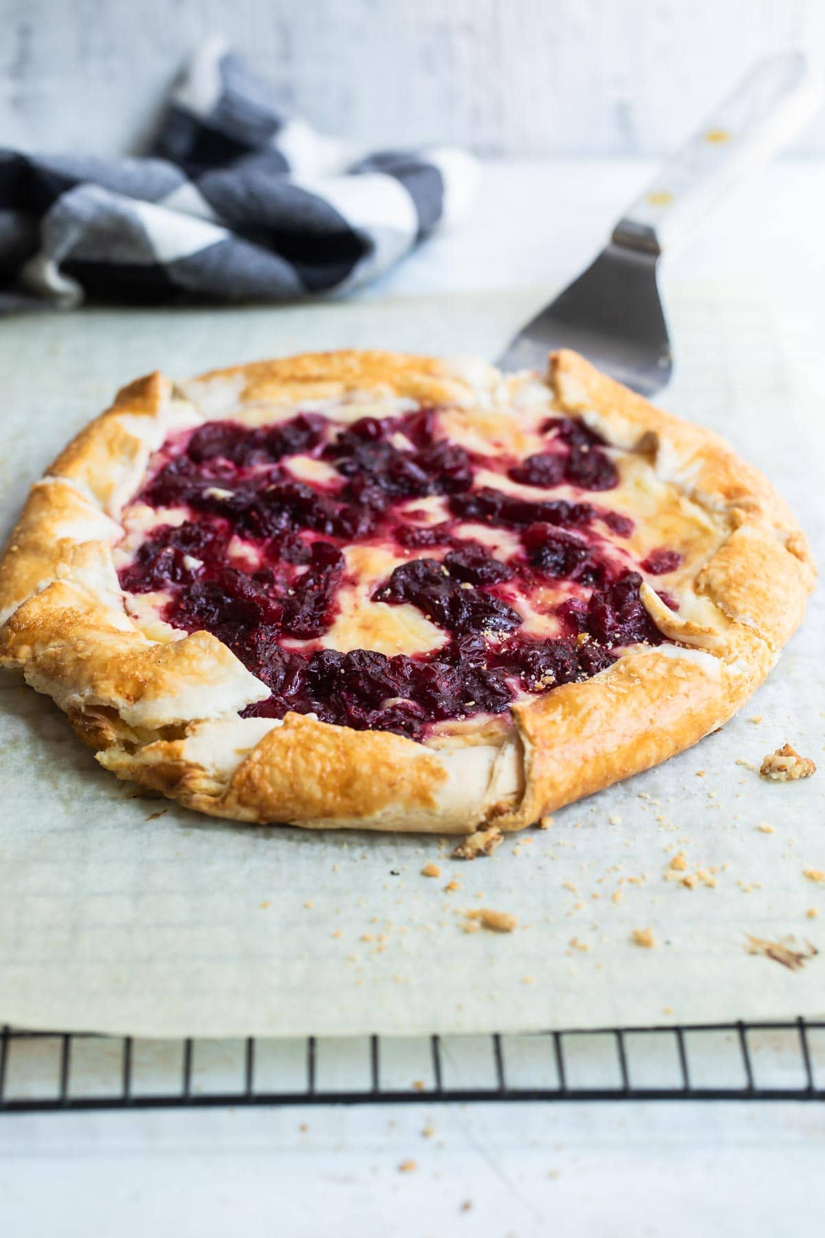 Cranberry cheesecake galette on a piece of parchment paper over a cooling rack.