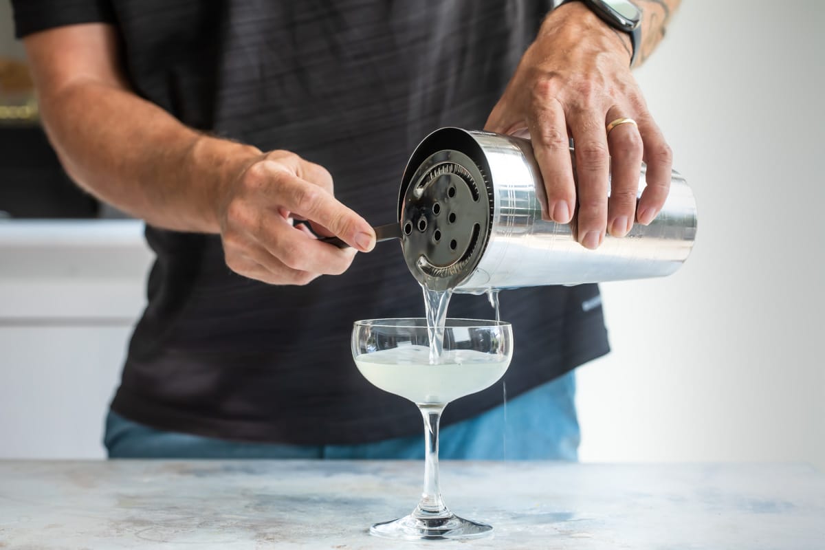 Straining a daiquiri into a cocktail glass.
