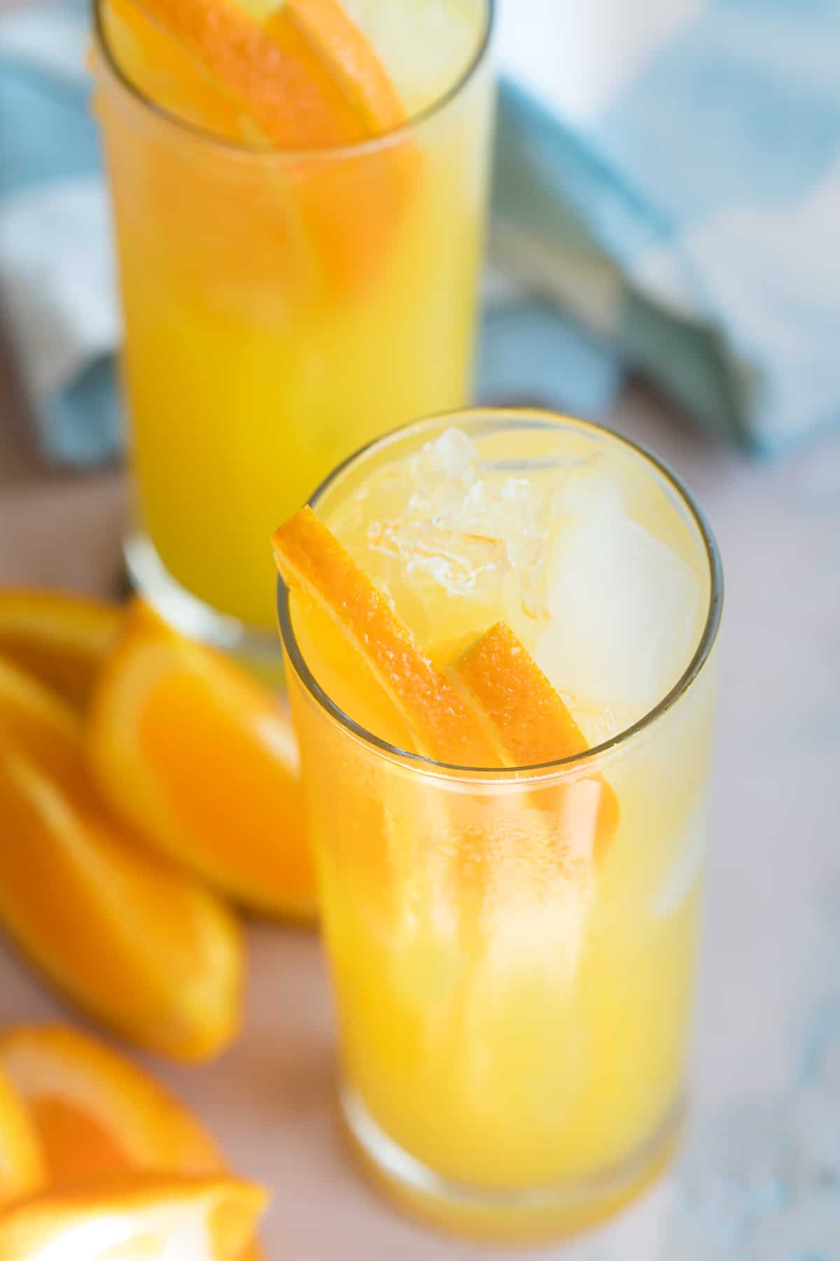 Two fuzzy navel cocktails surrounded by orange slices.