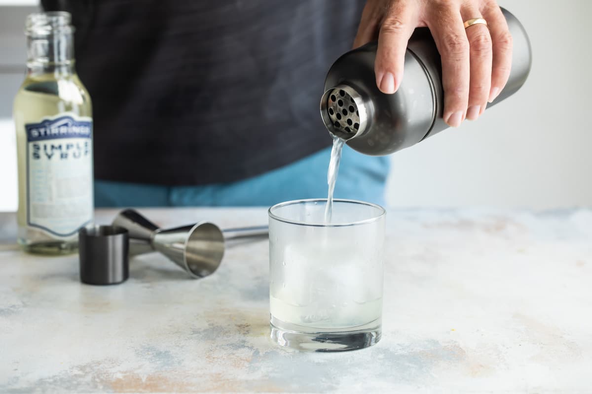 Straining a gin fizz into a lowball glass.