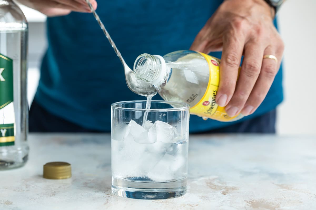 Mixing a gin and tonic in a glass.