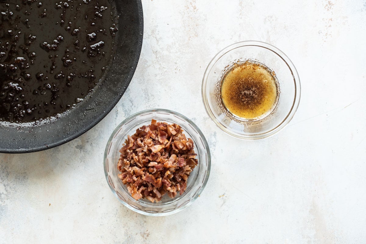 A ramekin of cooked bacon next to a ramekin of bacon fat.