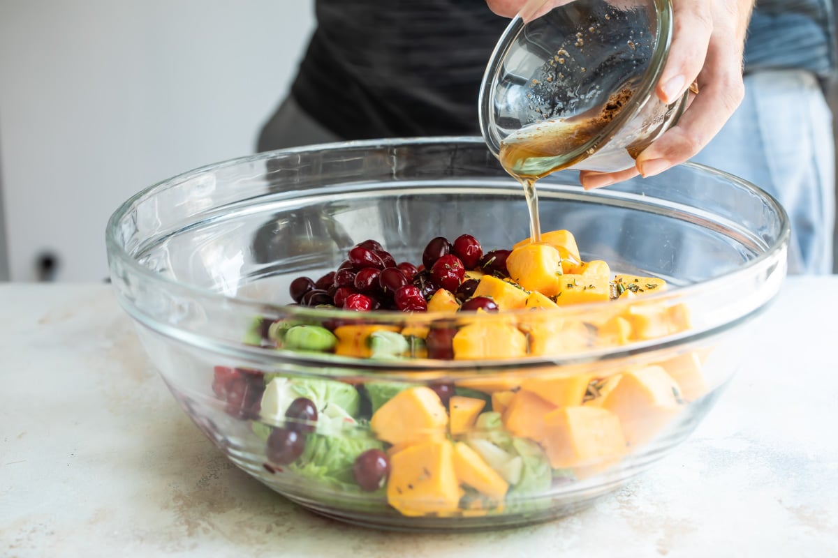 Someone pouring bacon fat on a bowl of vegetables.