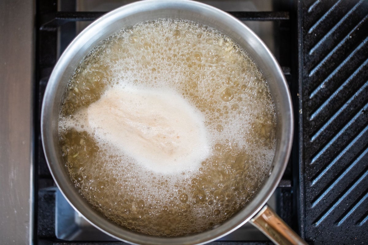 A silver pot with brown rice being boiled.
