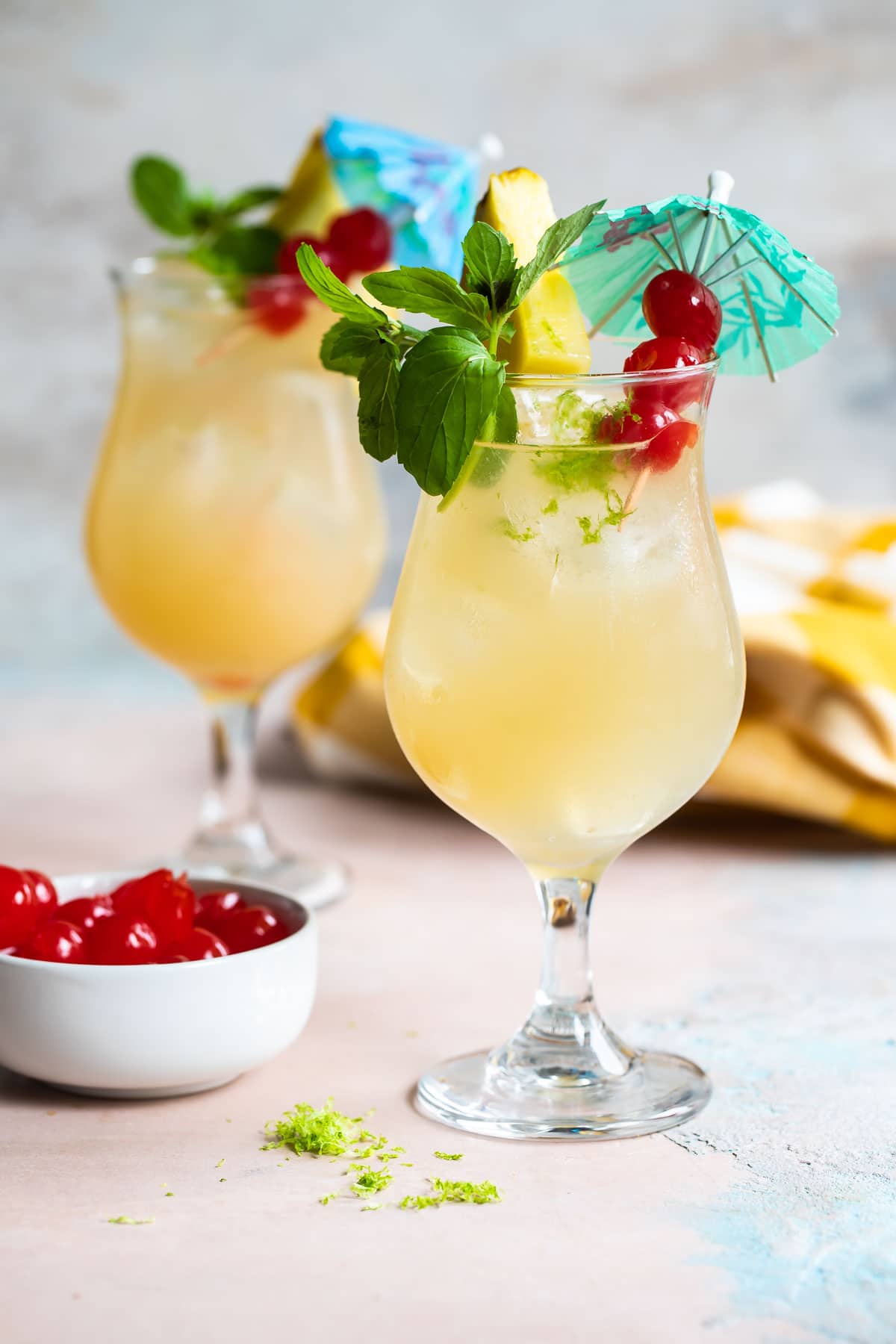 Two Mai Tai cocktails in hurricane glasses.