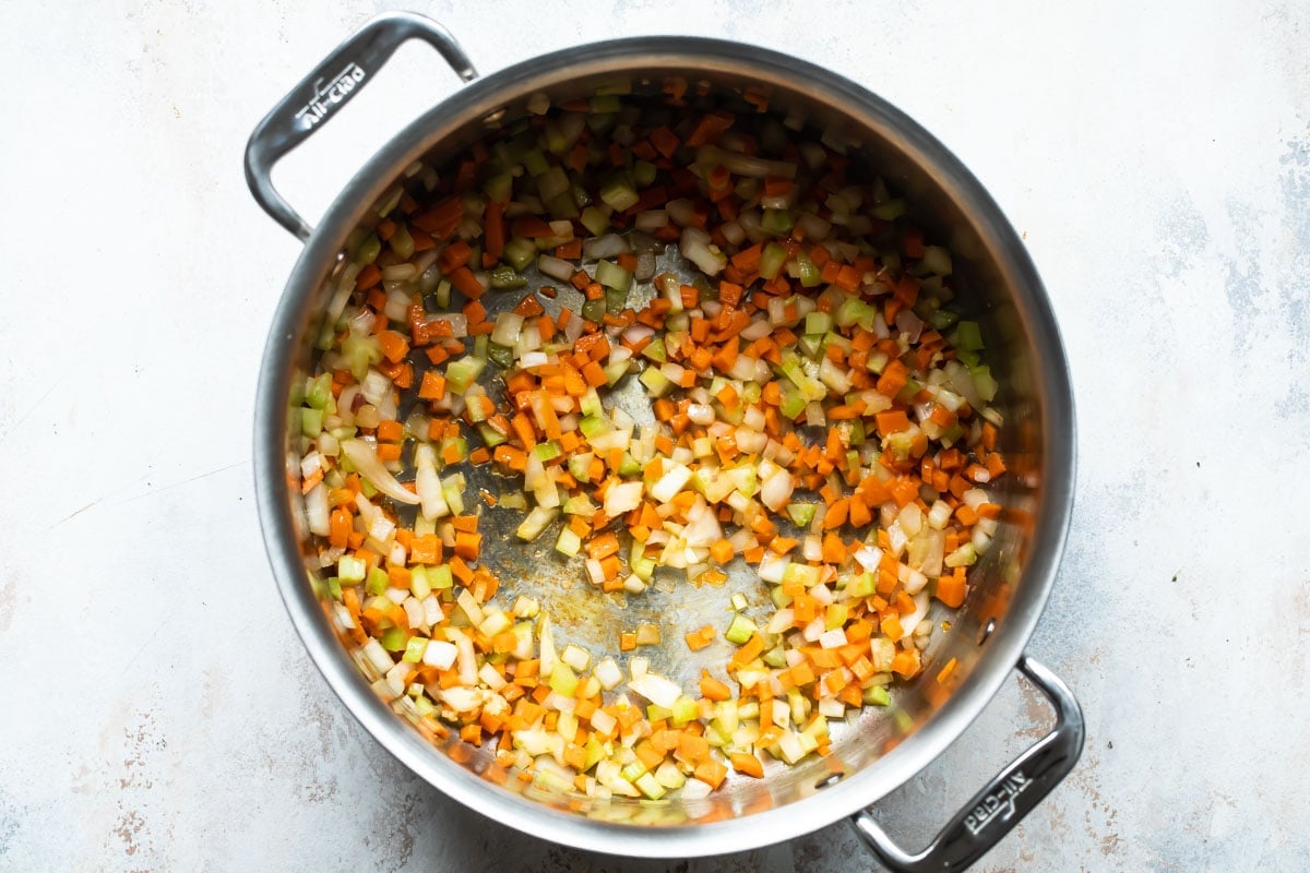 Onion, celery and carrot in a silver pot.