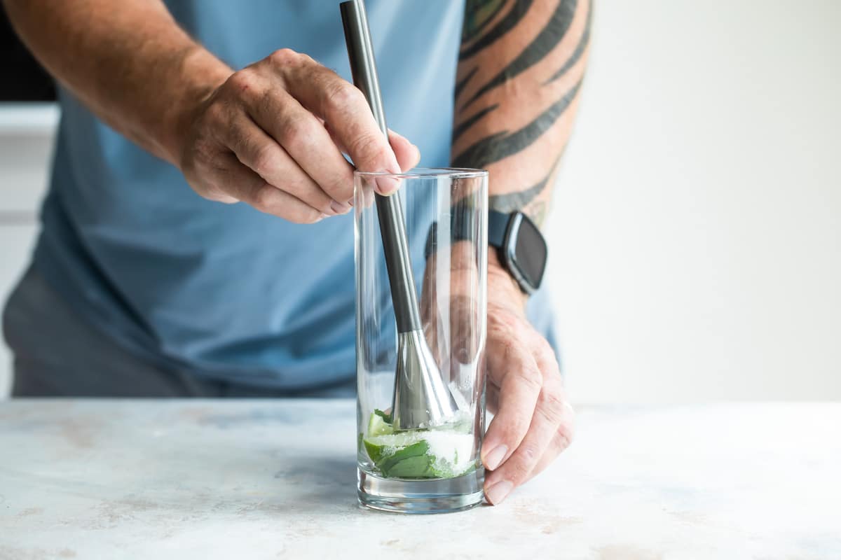 Muddling mint and lime in the bottom of a glass for a mojito.