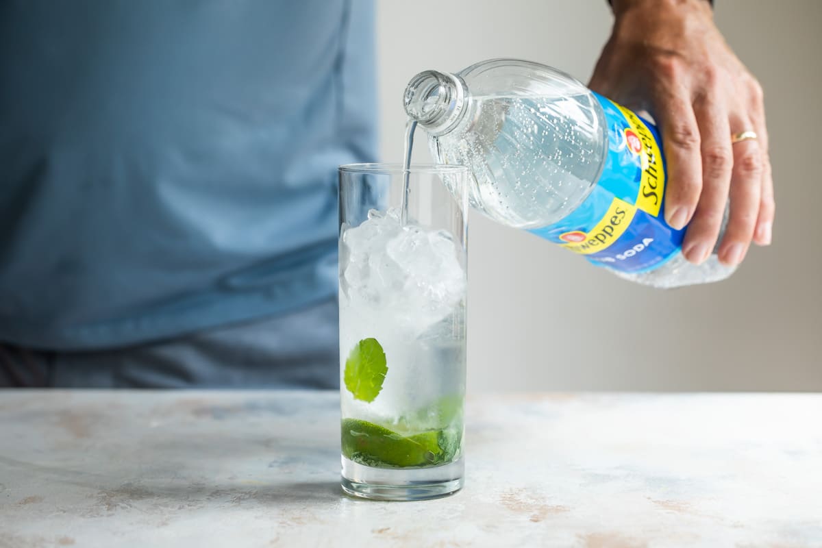 Adding club soda to a Mojito.