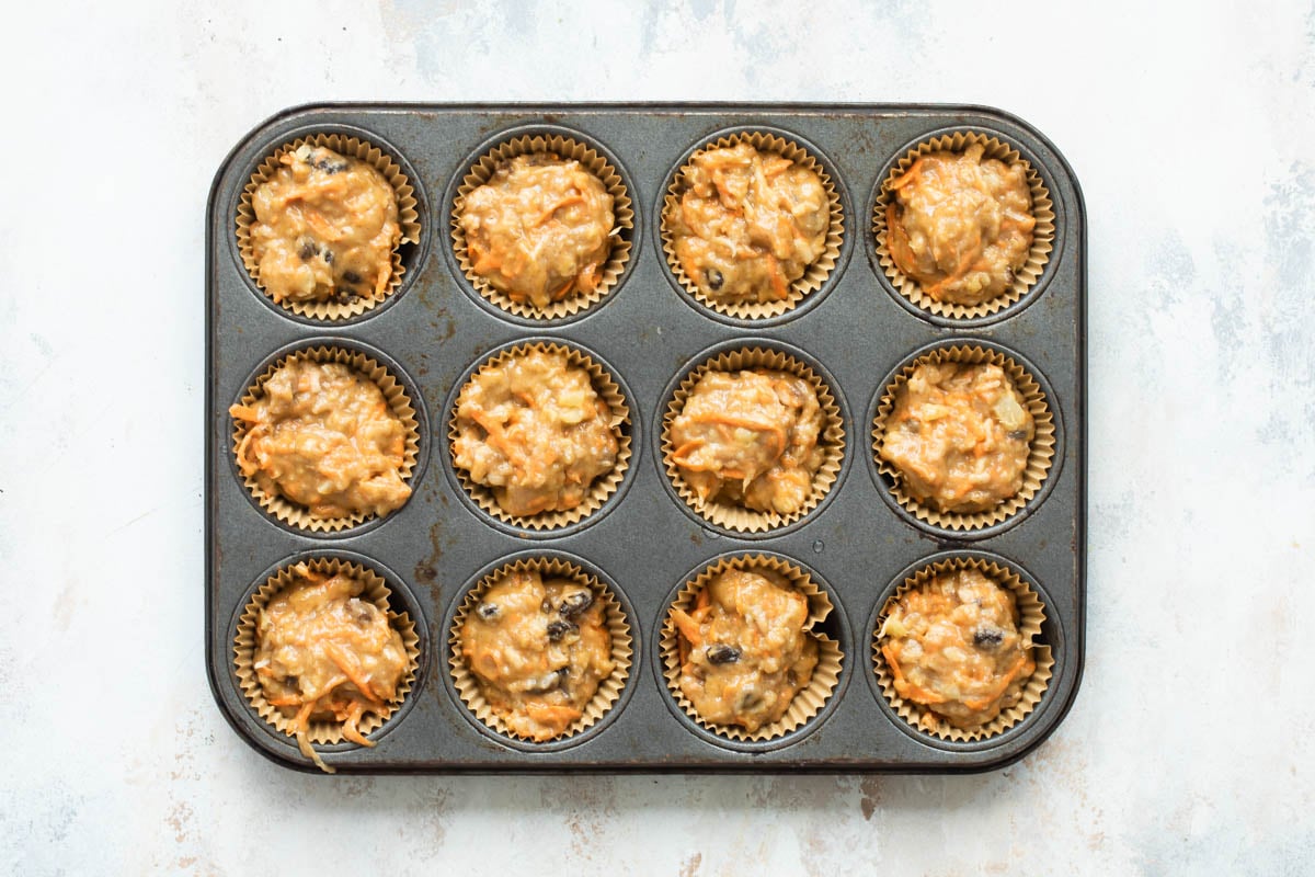 Twelve unbaked morning glory muffins in a muffin tin.