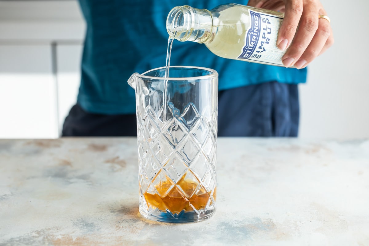 Mixing an Old Fashioned cocktail in a glass mixing glass.