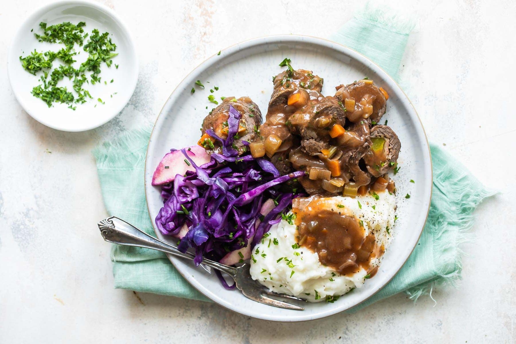 A plate with rouladen, braised red cabbage, and mashed potatoes.