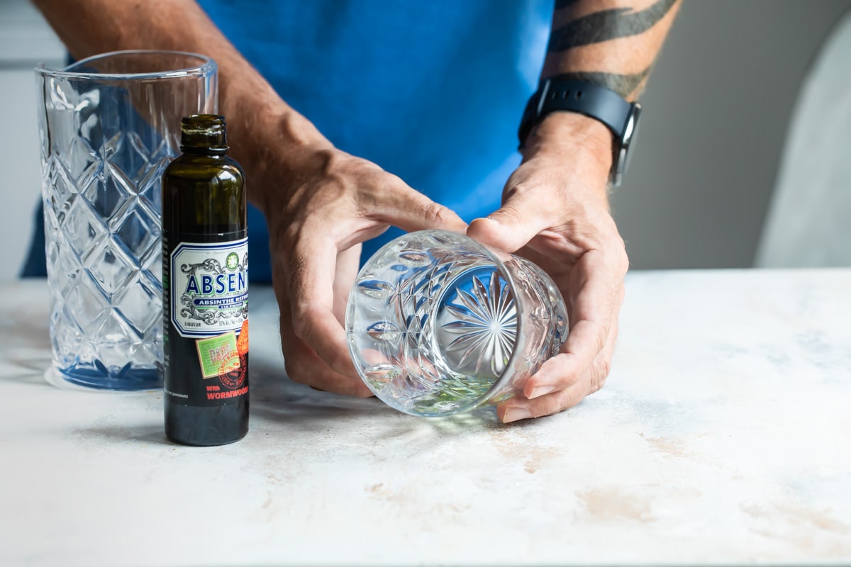 Swirling a glass with absinthe.