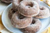 Seven apple cider donuts on a gray round plate.