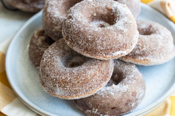 Seven apple cider donuts on a gray round plate.