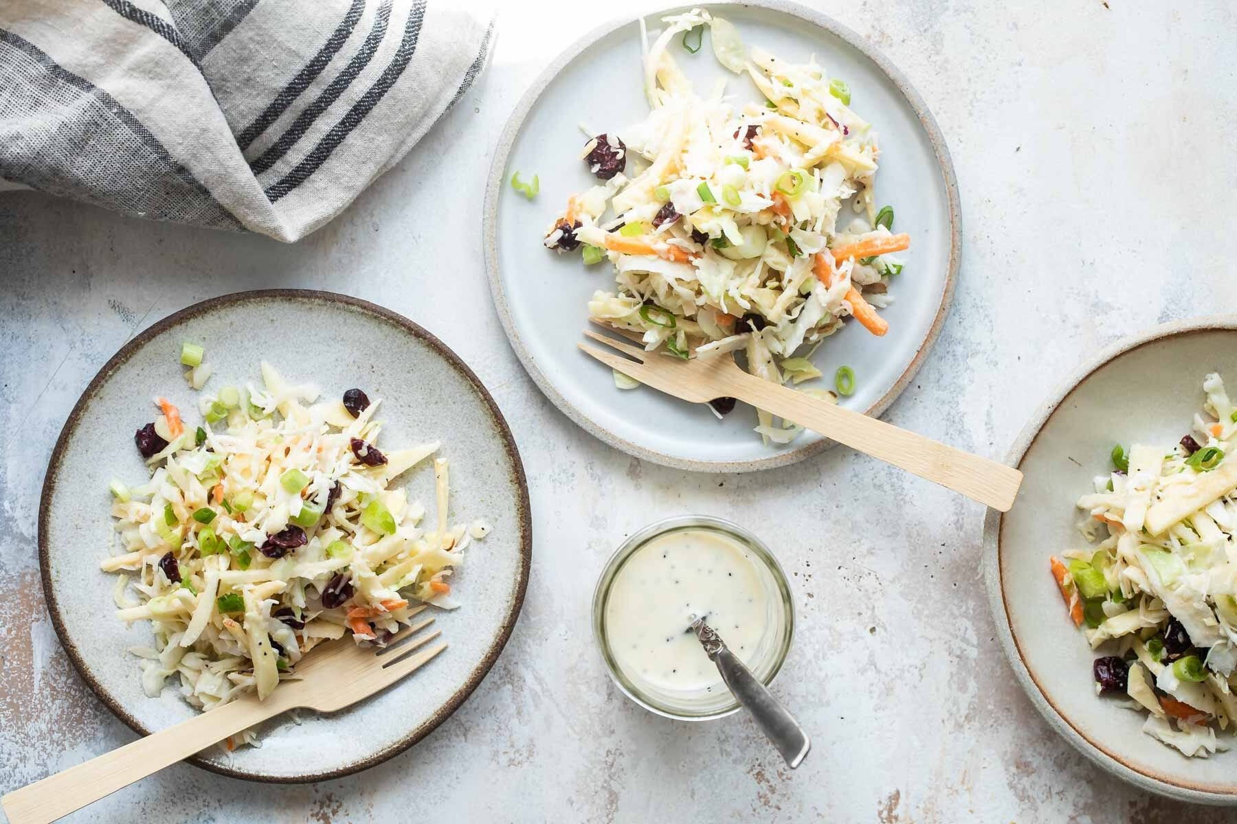 Apple coleslaw on three gray plates.