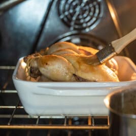 Brushing apple glaze on a Cornish hen.