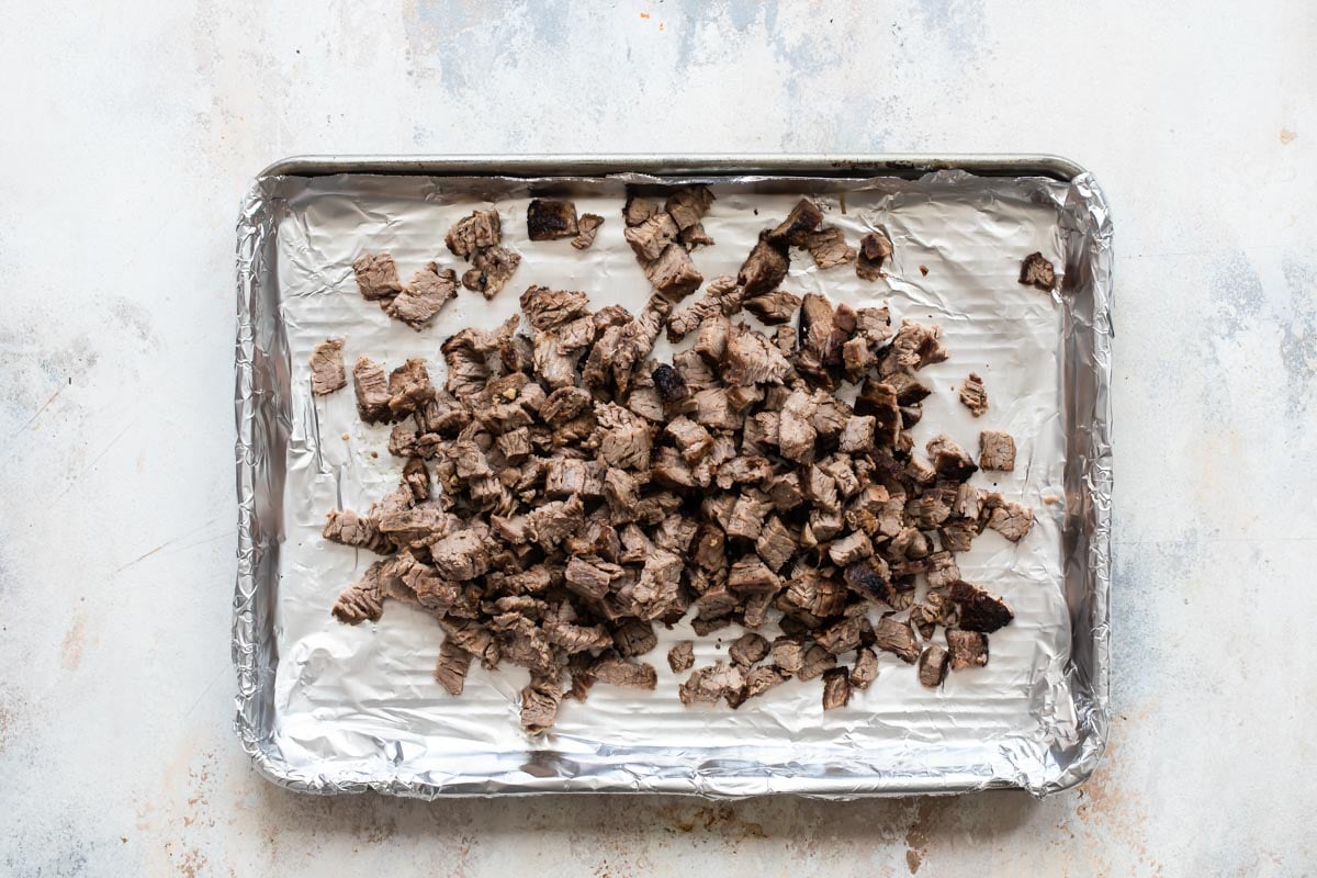 Cubed cooked beef on a baking sheet.