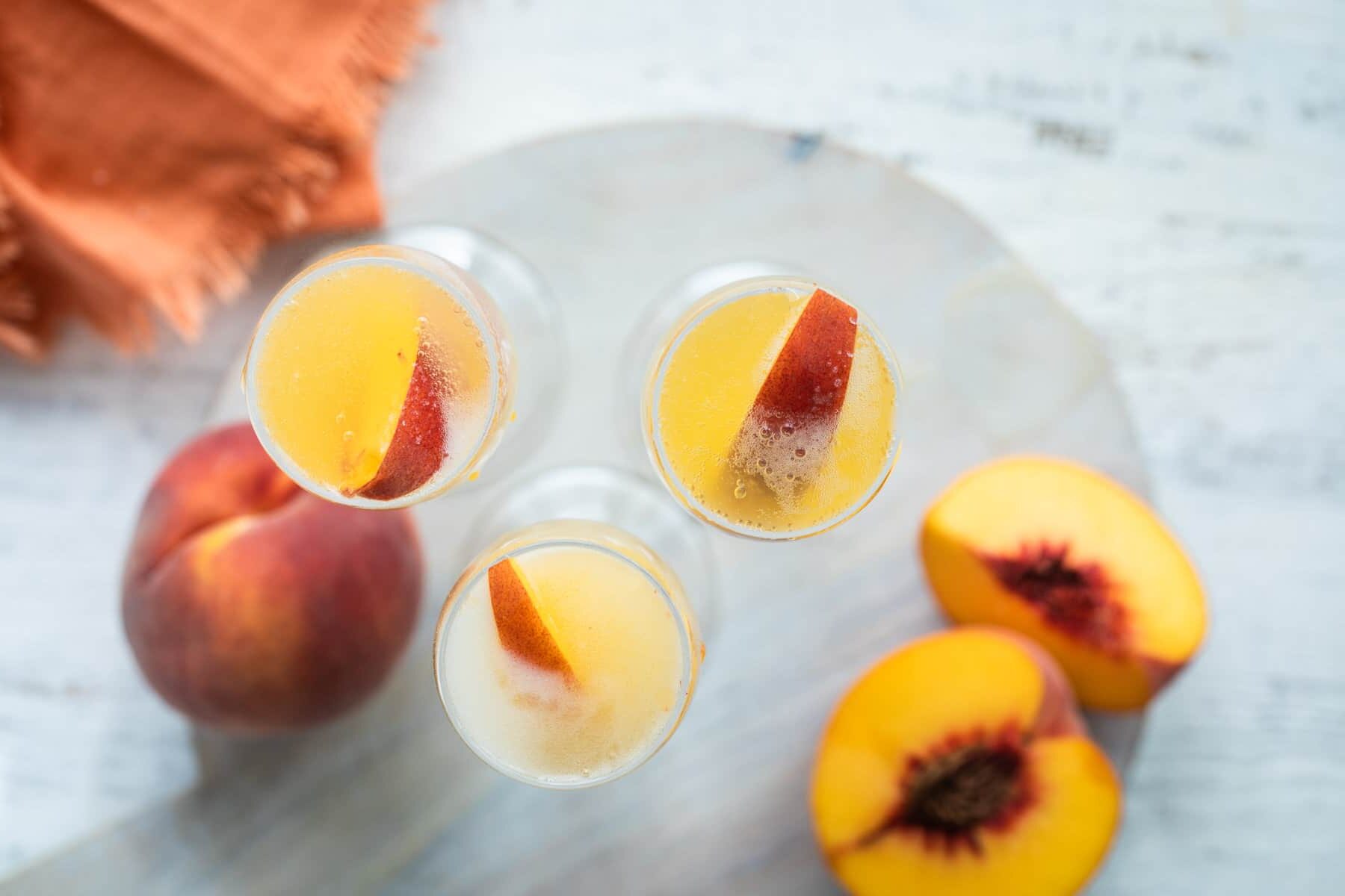 Three bellinis garnished with fresh peace slices.
