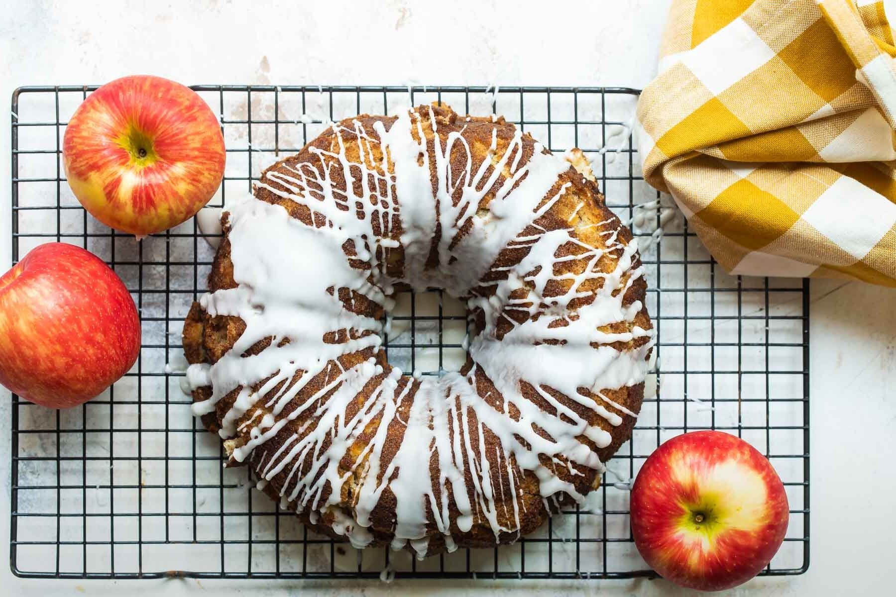 Cinnamon Apple Cake on a cooling rack surrounded by apples.