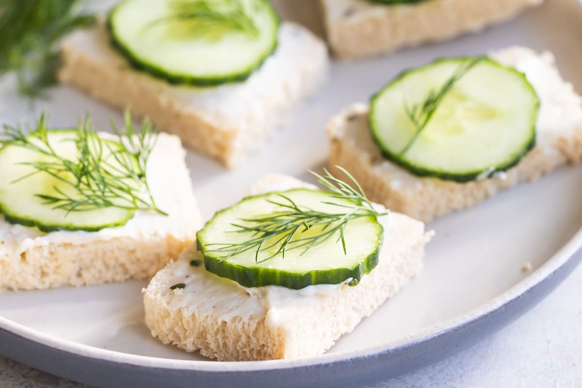 Cucumber sandwiches on a round white plate.
