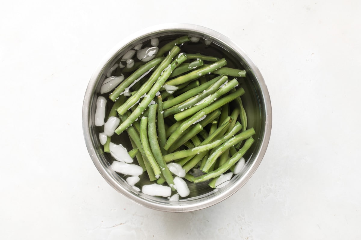 Blanched green beans in a bowl of ice water.