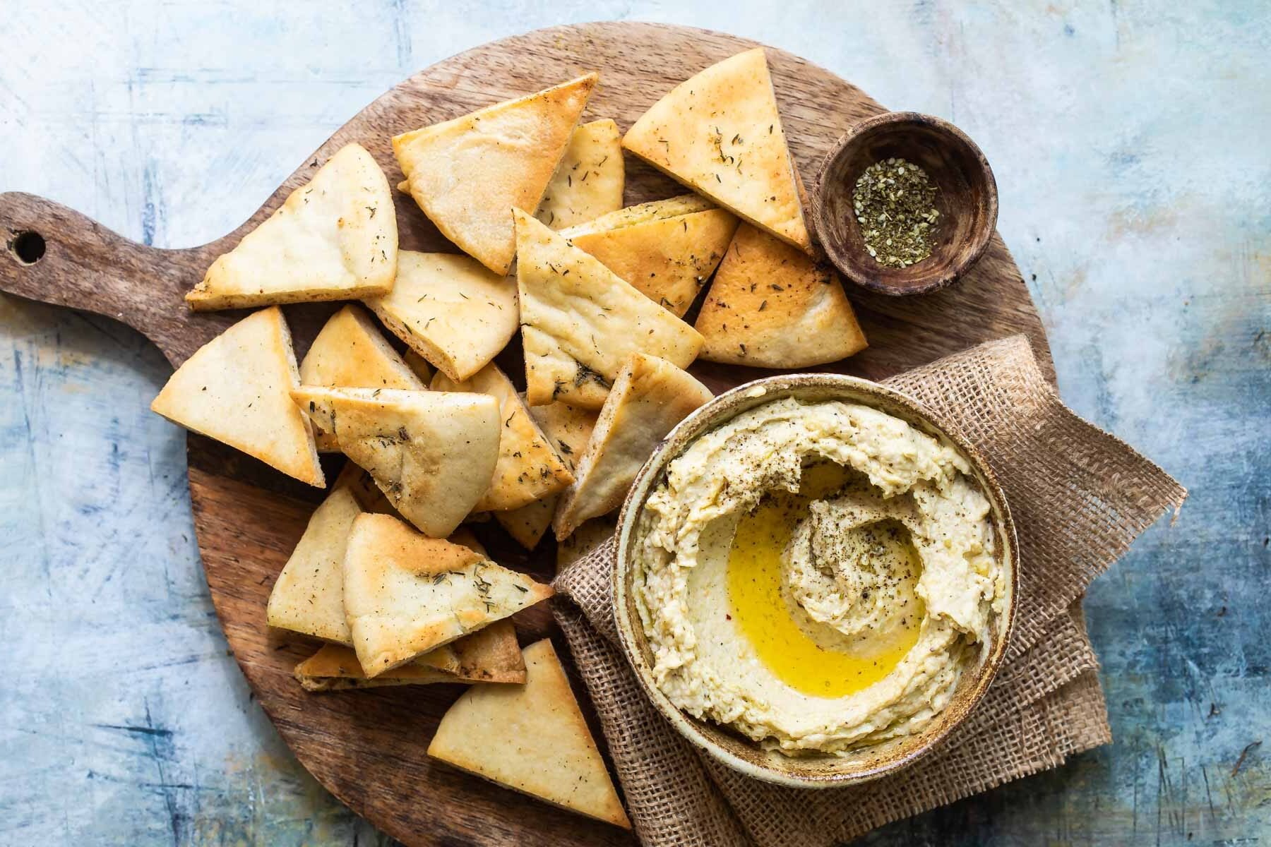 Homemade hummus with zaatar butter in a bowl with pita chips.