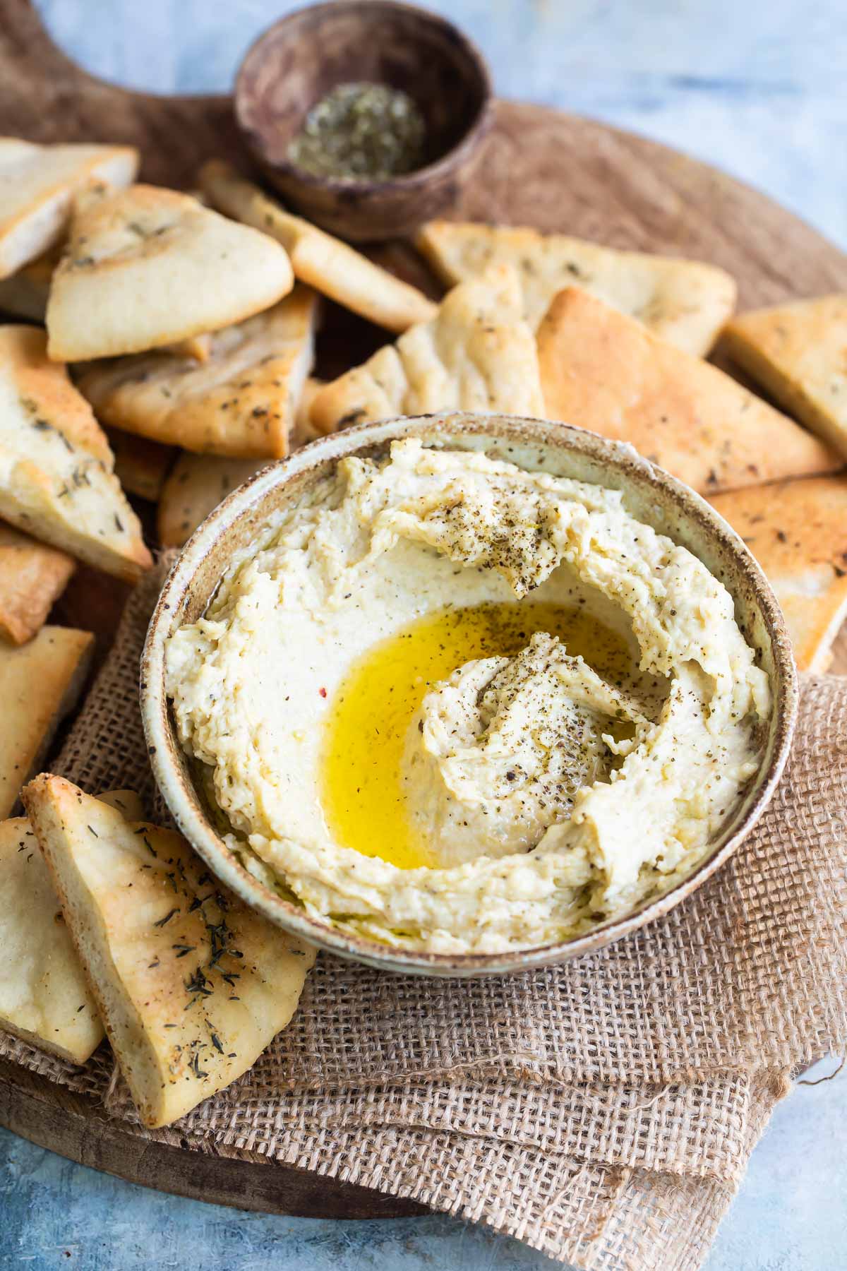 Homemade hummus with zaatar butter in a bowl with pita chips.