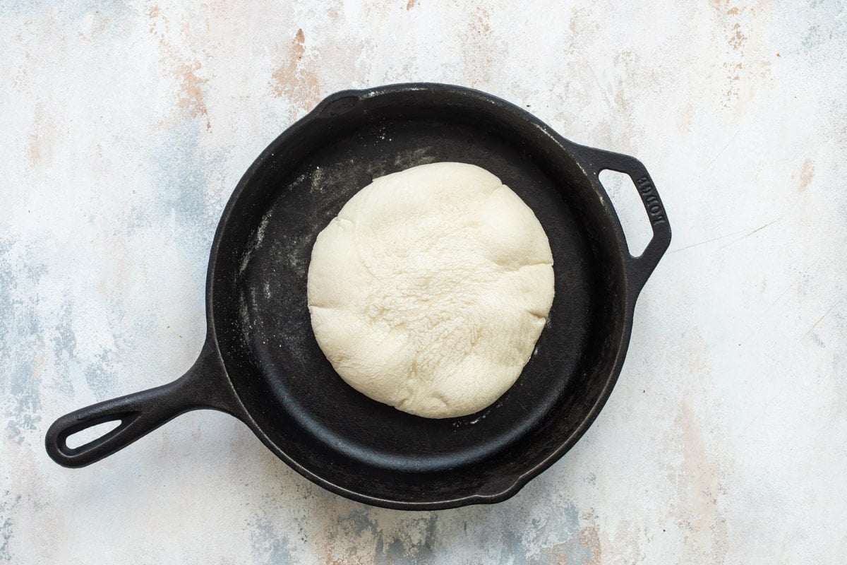 A slice of homemade pita bread on a cast iron skillet.