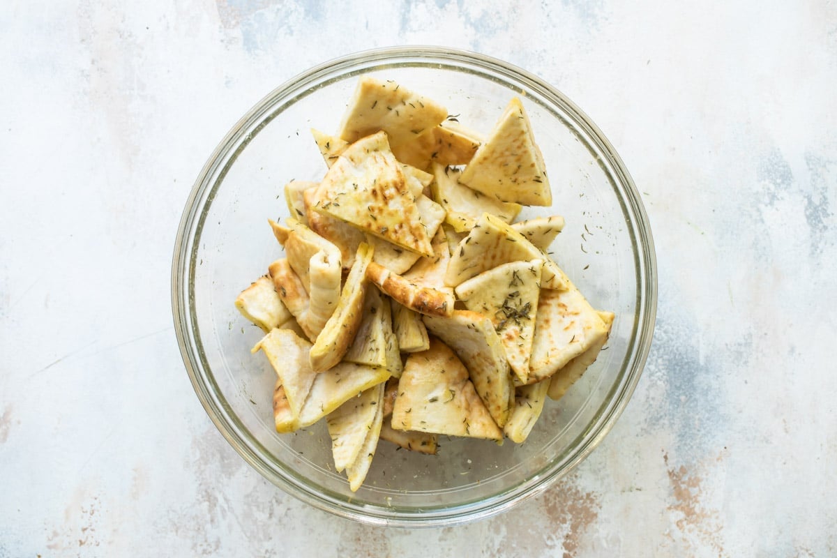Seasoned triangles of pita bread in a glass bowl.
