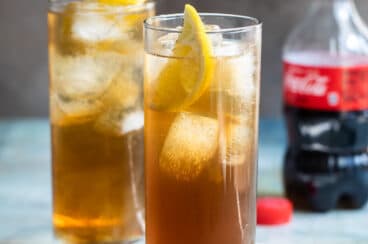 Two long island iced teas with a bottle of Coke in the background.