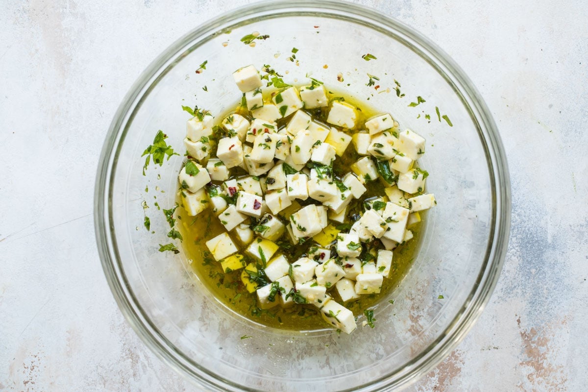 Marinated feta in a clear bowl.