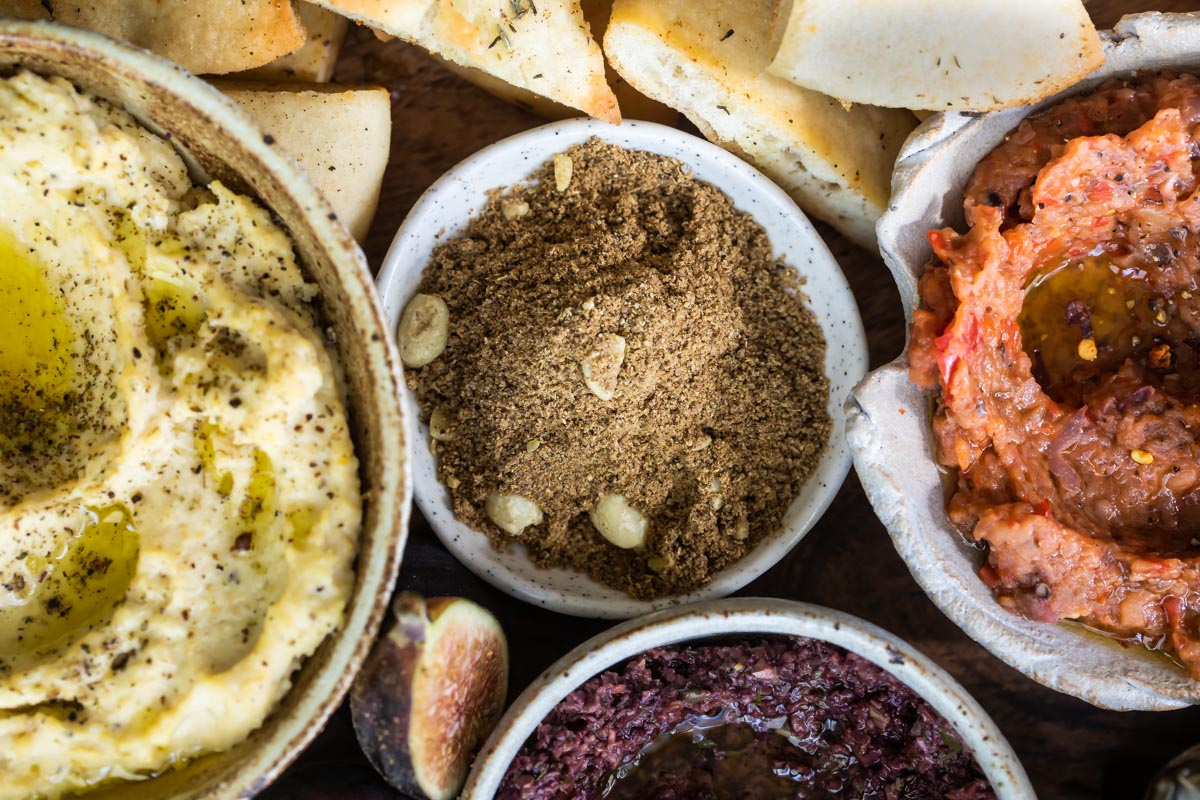 Dukkah, eggplant dip, and hummus dip in bowls.