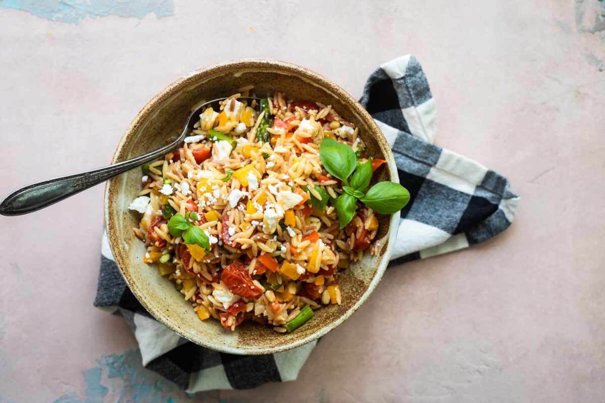 Orzo pasta salad in a bowl with a spoon.