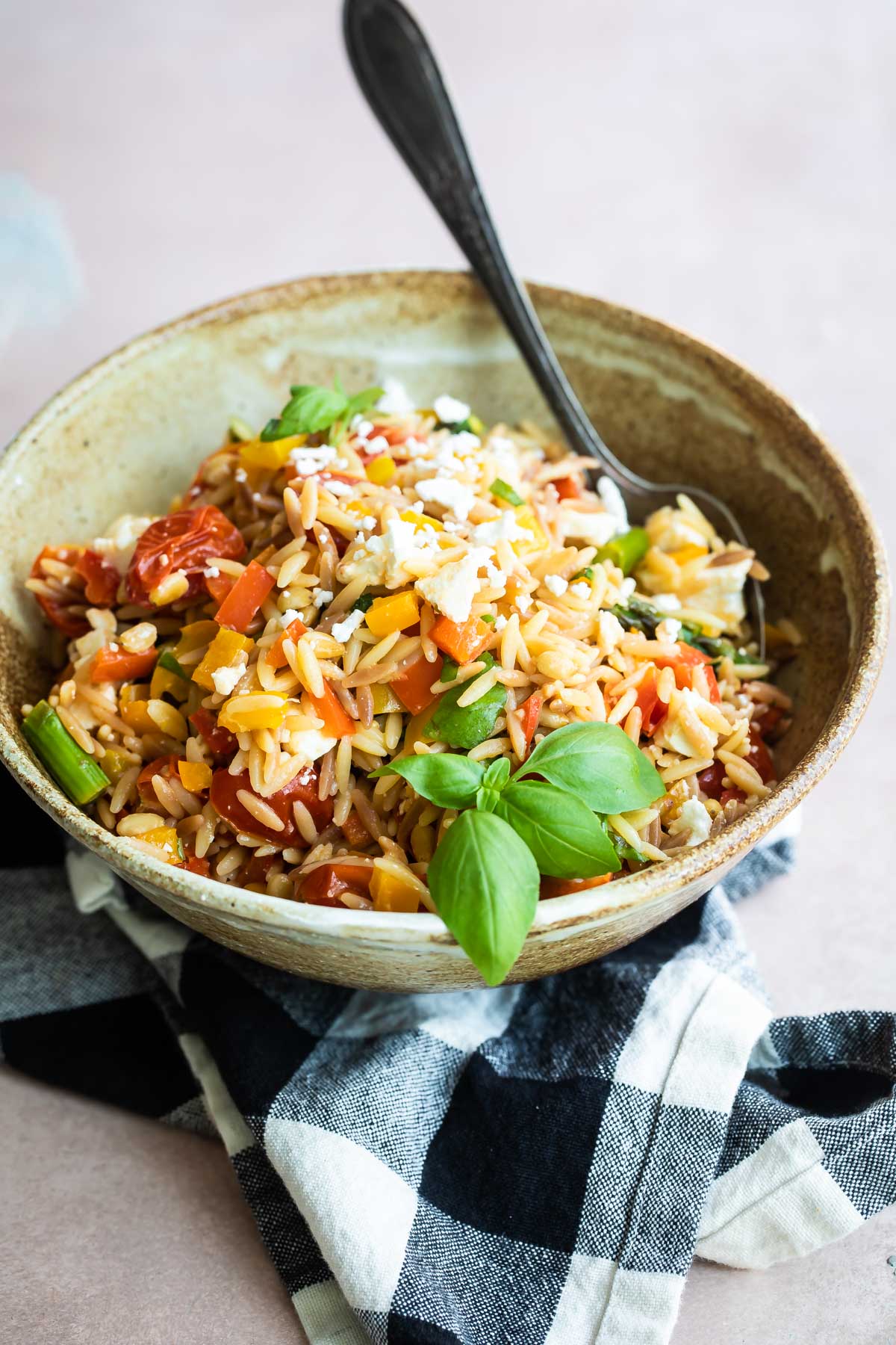 Orzo pasta salad in a bowl with a spoon.
