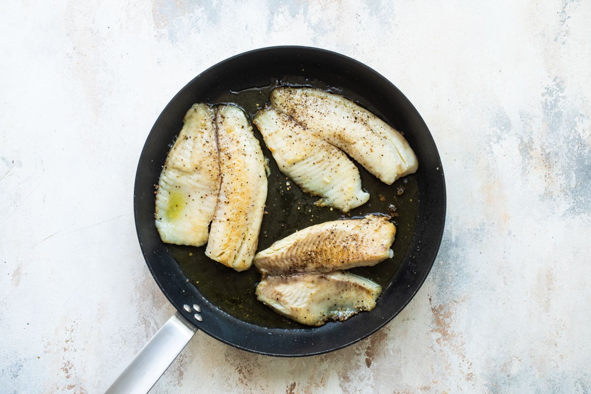 Pan fried tilapia on a skillet.