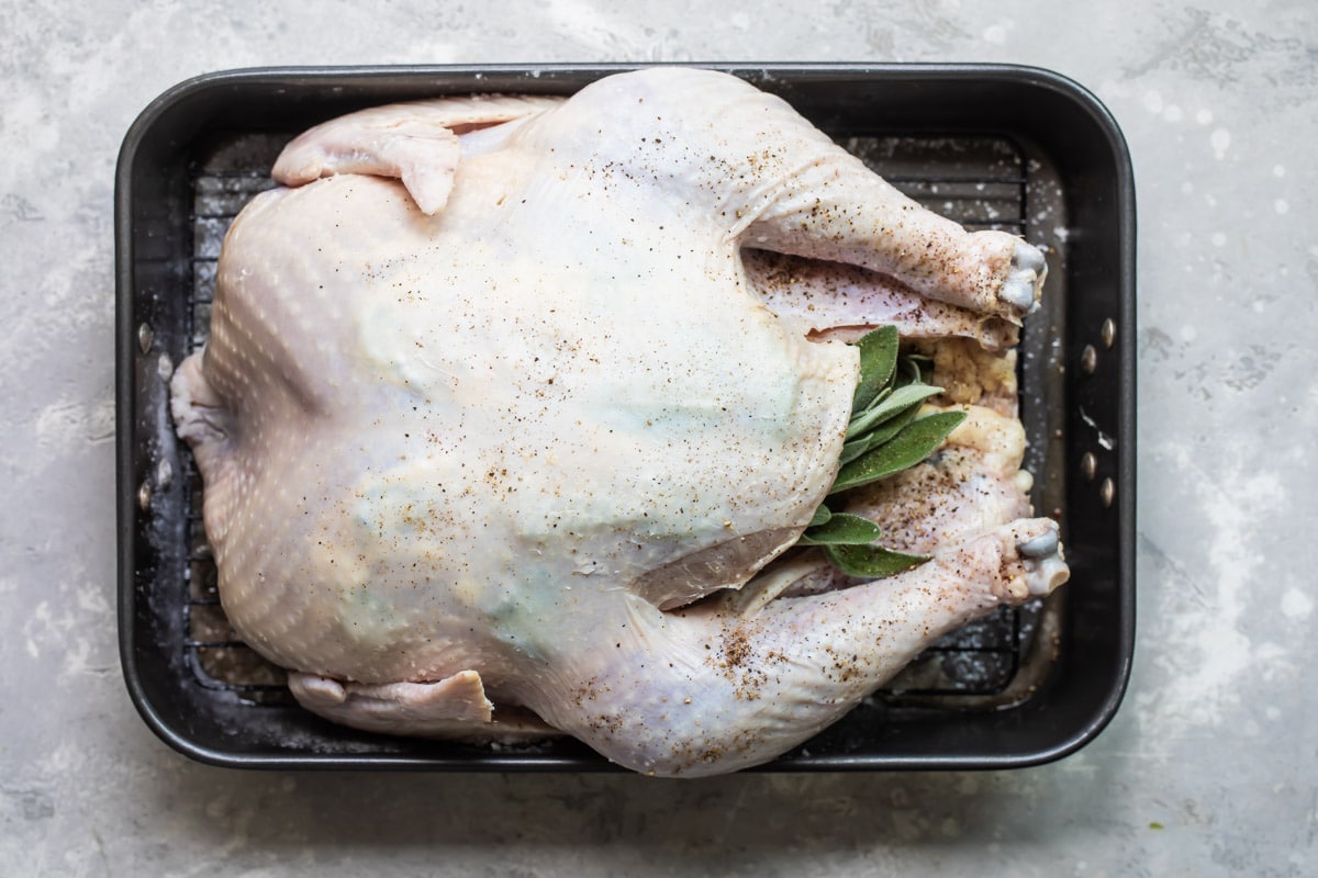 Sliding fresh sage leaves under the skin of a raw turkey.