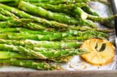 A baking sheet full of roasted asparagus with lemons.