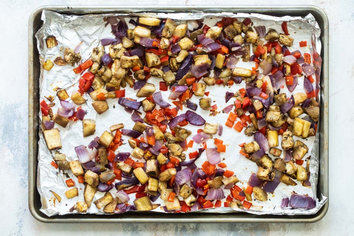 Roasted eggplant and veggies on a baking sheet.
