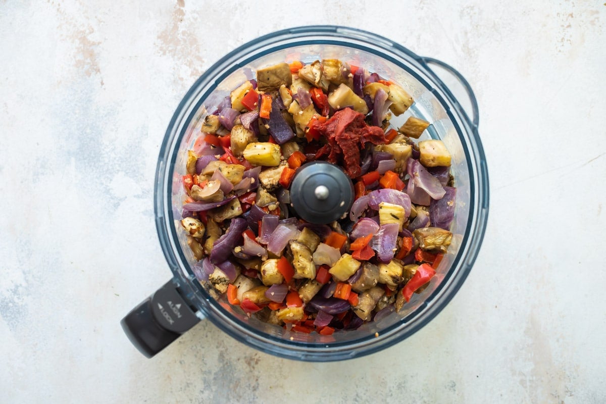 Roasted eggplant and veggies cubed in a food processor.