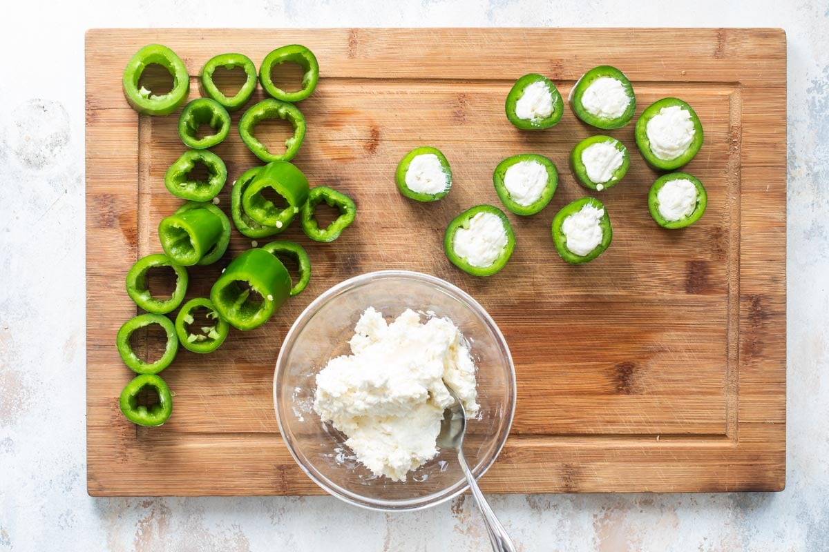 Filling jalapeño rings with cream cheese filling.