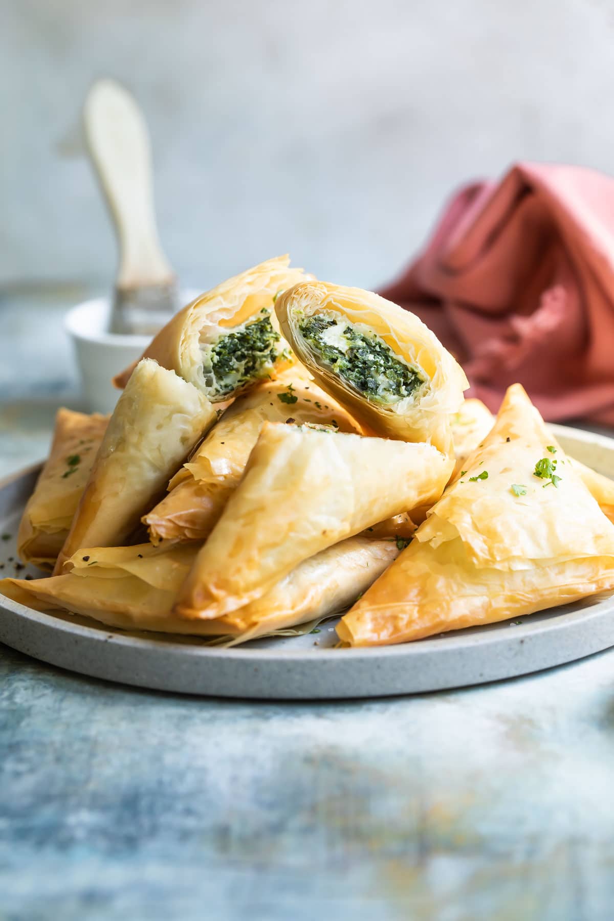 A pile of three cheese spanakopita triangles on a plate.
