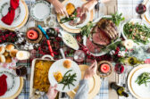 A Christmas table with prime rib, scalloped potatoes, green beans, and rolls.